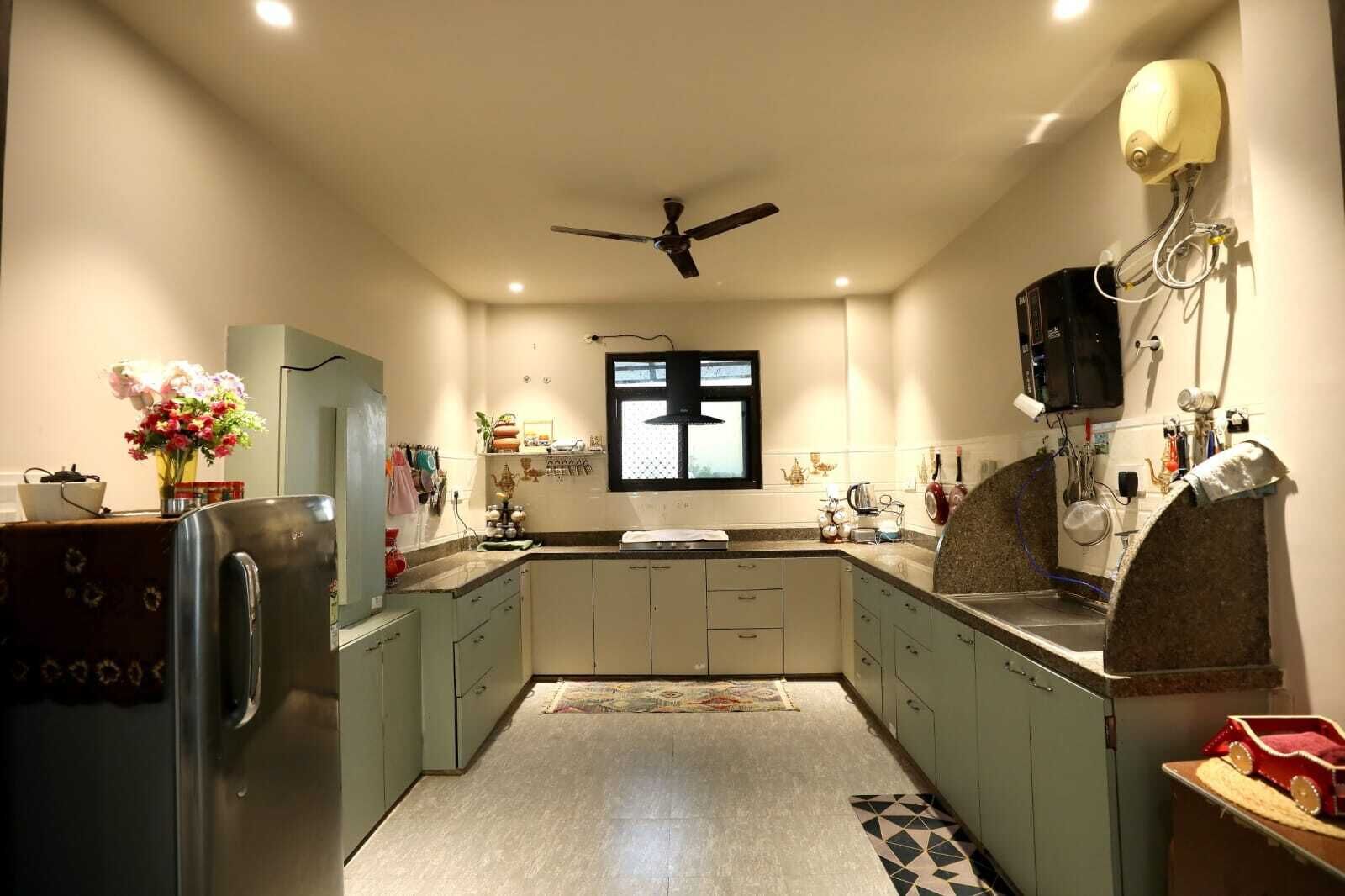 A kitchen with a refrigerator, stove, sink, and ceiling fan.
