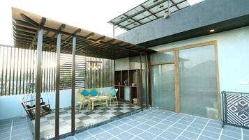 Un espacio de estar al aire libre cubierto con piso a cuadros, una hamaca y un vidrio que da a una habitación.