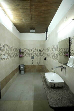 A bathroom with a wooden ceiling, patterned walls, a sink, a mirror, and a shower area. - The Nivaas At Berhin's Farmstay (Ajmer)