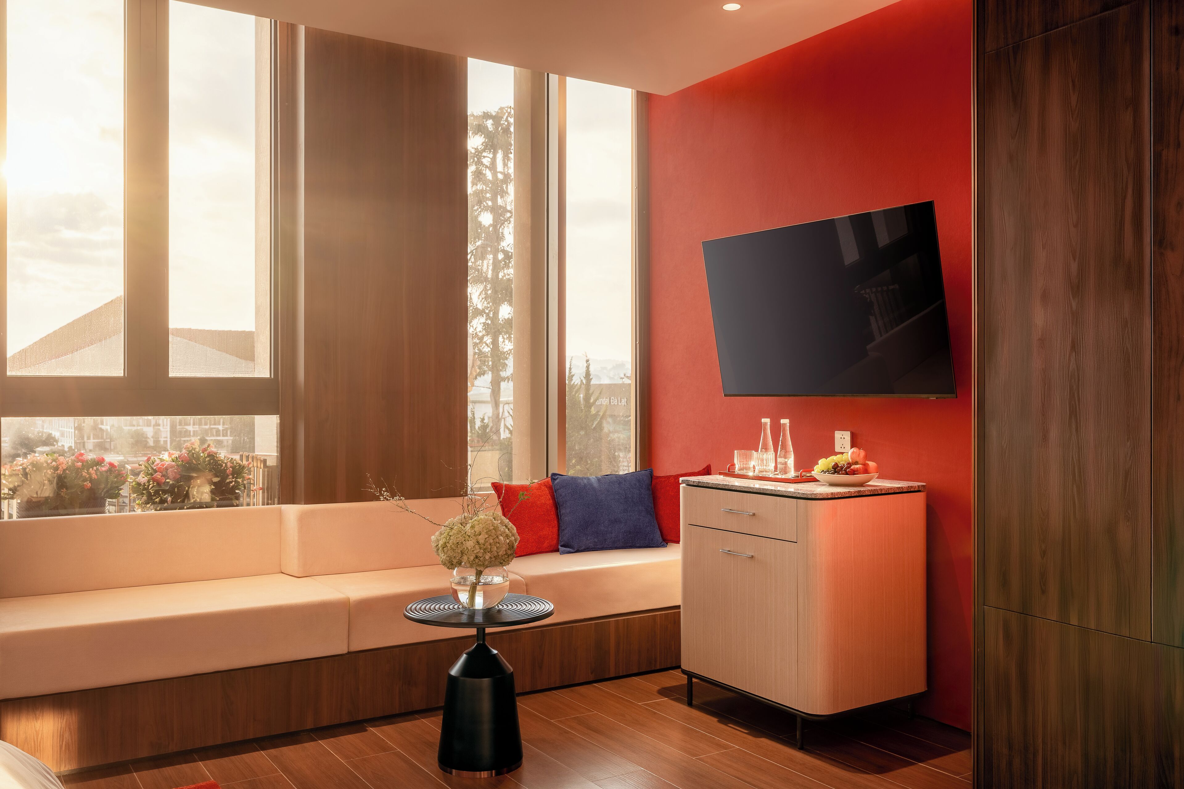 A modern living room with a sofa, a small table with a vase, a cabinet, and a TV mounted on the wall.