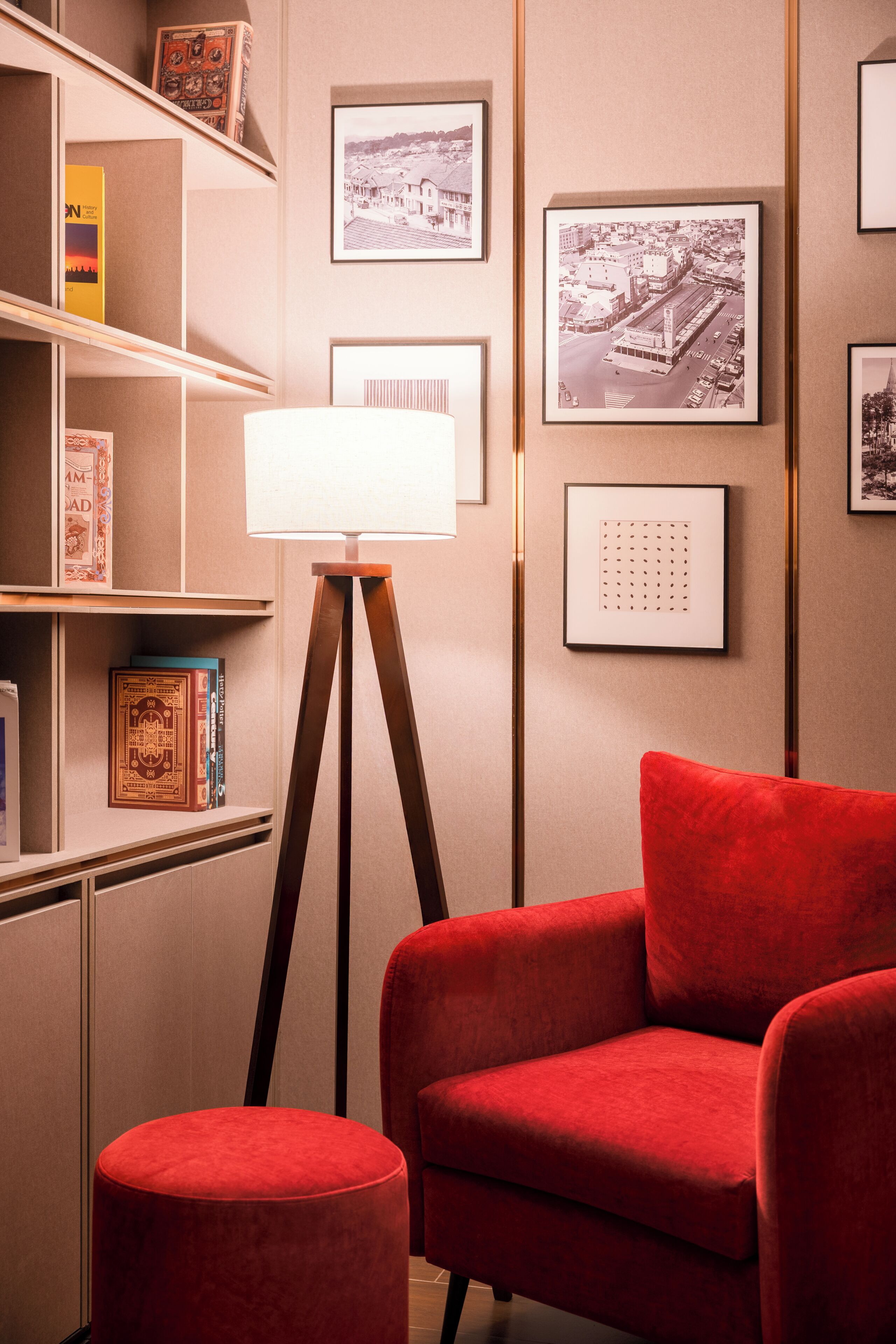 A room with a red armchair, a floor lamp, and framed pictures on the wall.