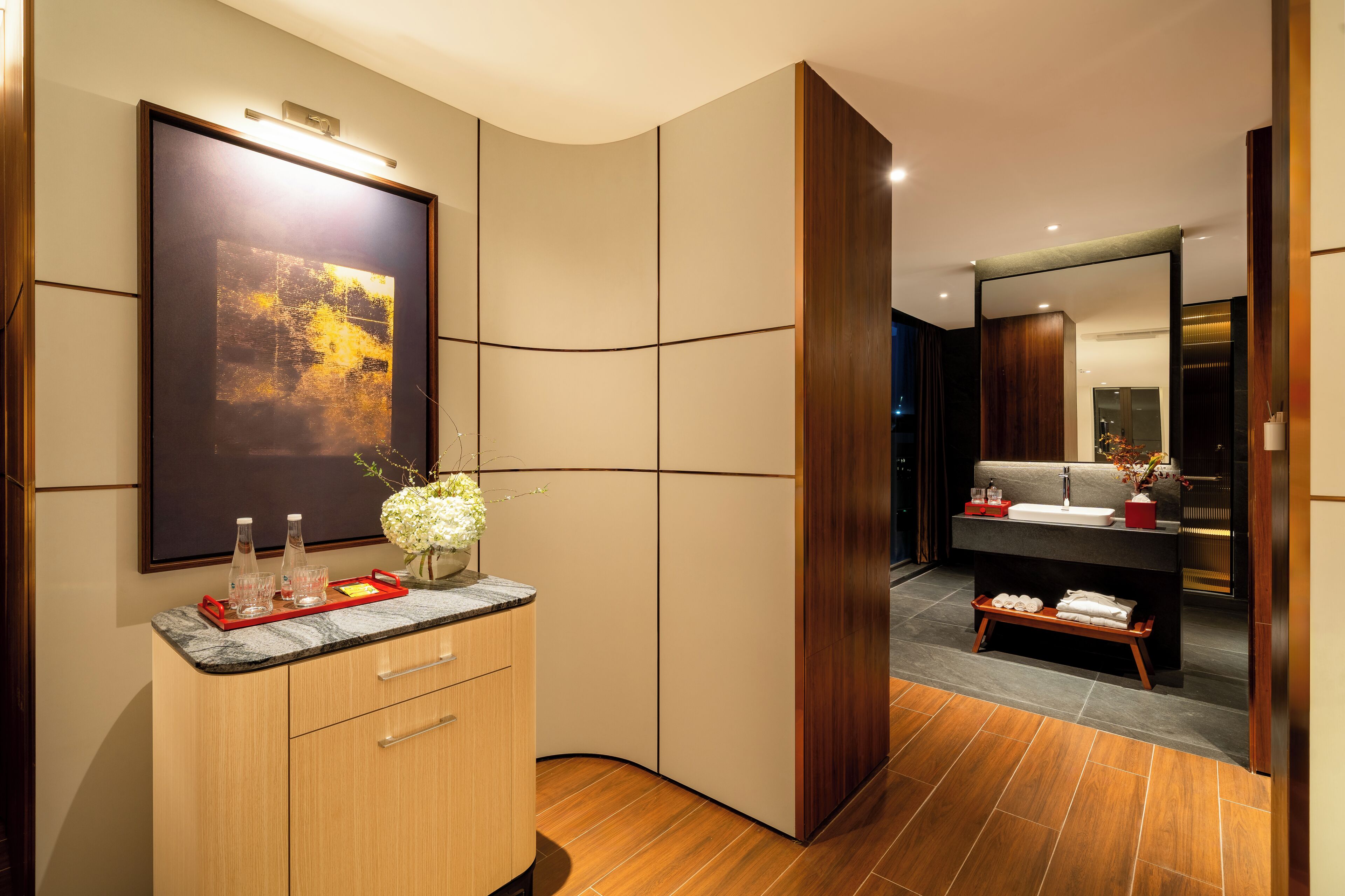 A modern bathroom with a vanity, mirror, and a large framed artwork.
