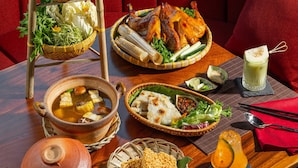 Une table à manger avec différents plats, notamment un poulet rôti, des légumes et une soupière.