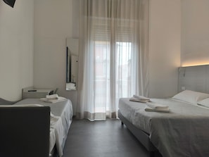 A hotel room with two beds, a mirror, a bedside table, and a chair. - Hotel Otello (Punta Marina)