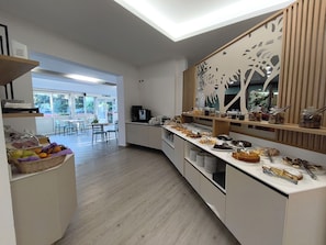 Una cocina moderna con un bufé de desayuno, que incluye frutas, pasteles y una estación de café.