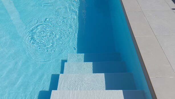 A swimming pool with clear blue water and a set of steps leading into it. - Hotel Otello (Punta Marina)