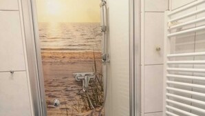 Ein Badezimmer mit Glastür, Dusche und Meerblick.