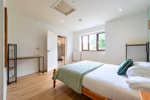 Une chambre à coucher avec un lit, une fenêtre, une porte donnant sur une salle de bain et une petite table.