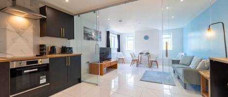 A modern kitchen with a built-in oven and a dining area with a table and chairs.