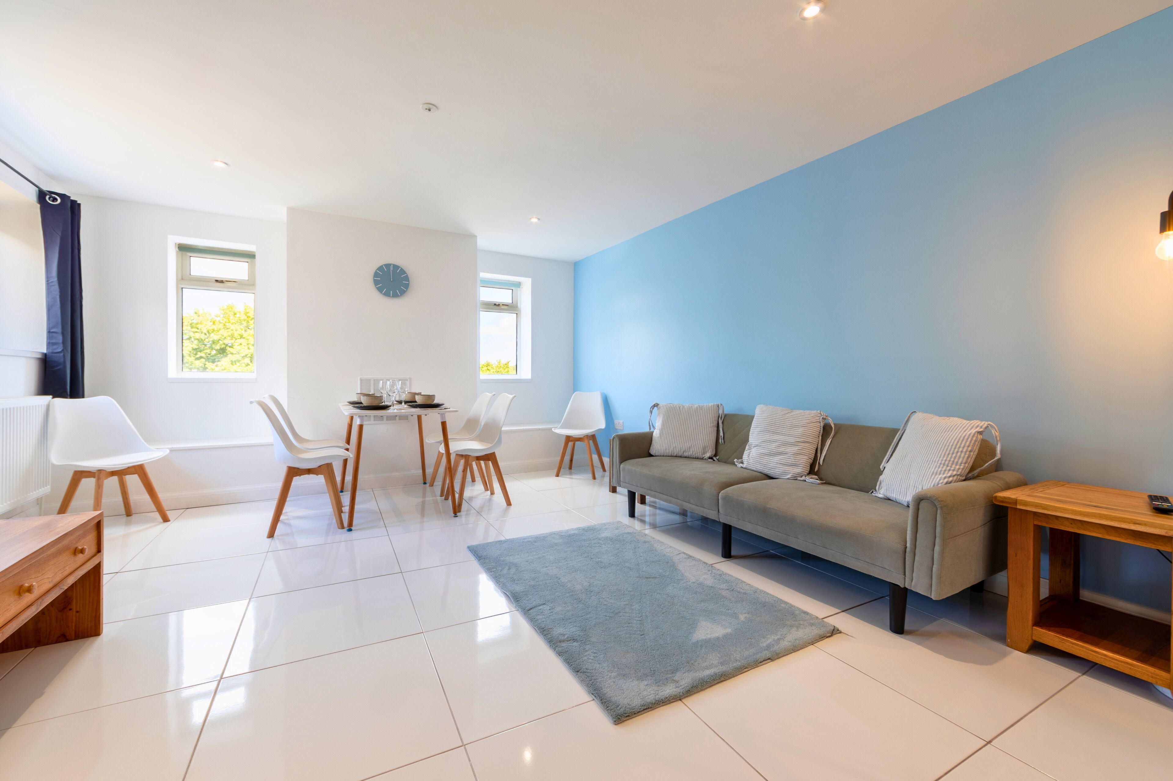 A modern living room with a sofa, chairs, a dining table, and a rug.