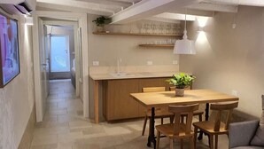 A modern kitchen with a wooden island, a dining area with chairs, and a hanging light fixture. - Dimore del Borgo Antico Corte da Lezze Luxury House Venice (Venezia)