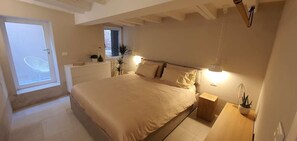 Een slaapkamer met een groot bed, nachtkastjes, een raam en een klein bureau.