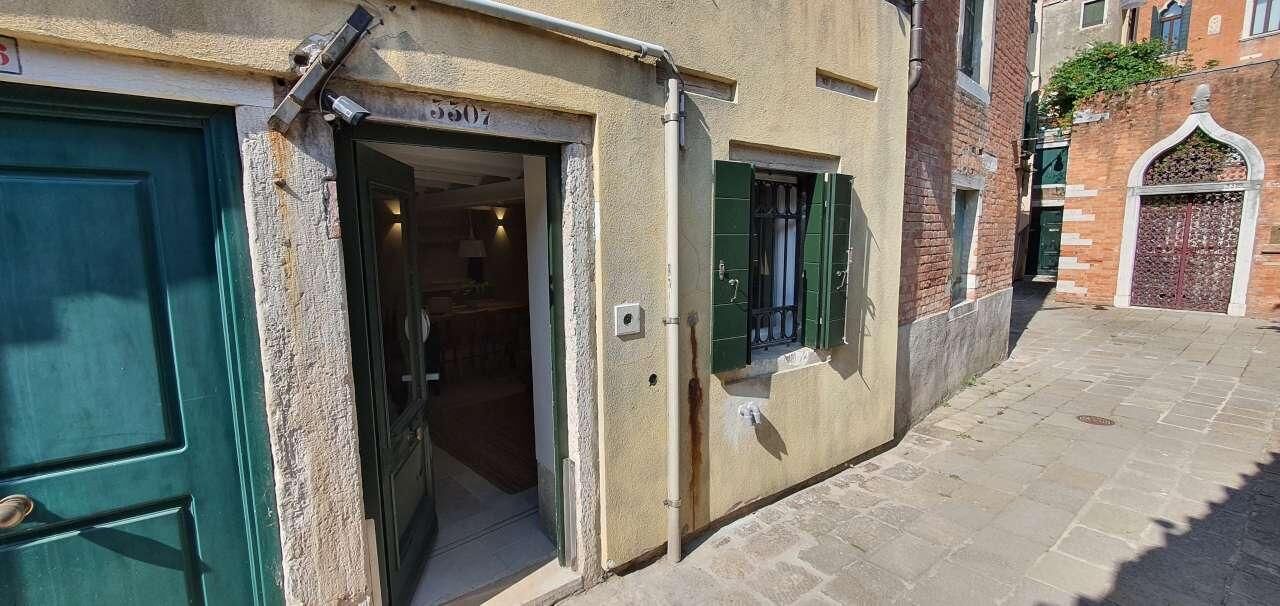 Un vicolo stretto con l'ingresso di un edificio, una porta verde e una finestra con persiane.