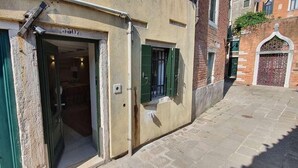 A narrow street with a building entrance, a green door, and a window with shutters. - Dimore del Borgo Antico Corte da Lezze Luxury House Venice (Venezia)