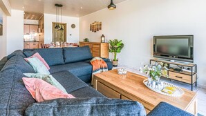 A modern living room with a sectional sofa, a wooden coffee table, and a flat-screen TV. - Nice apartment for 4 guests with WIFI and TV (Bruges)