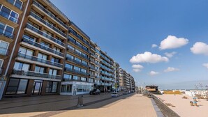 A multi-story hotel with balconies, a beachside location, and a paved walkway. - Nice apartment for 4 guests with WIFI and TV (Bruges)