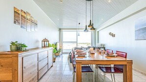A spacious dining area with a wooden table set for six, flanked by red chairs. A large window provides a view of the outdoors. - Nice apartment for 4 guests with WIFI and TV (Bruges)
