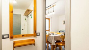 A hallway with a wooden-framed mirror, a wooden shelf, and a dining area with a table and chairs. - Cosy apartment for 4 people with WIFI, TV, balcony and pets allowed (Scalcoggia)