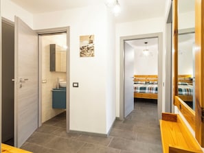 Ein modernes Schlafzimmer mit einem hölzernen Bett, einem Nachttisch und einer Pendelleuchte.