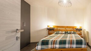 A bedroom with a wooden bed, a modern pendant light, and a door with a handle. - Cosy apartment for 4 people with WIFI, TV, balcony and pets allowed (Scalcoggia)