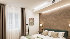 Ein Hotelzimmer mit einem Bett, einem Nachttisch, einer Wandlampe und einem dekorativen Schild.