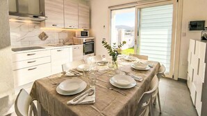 A modern kitchen with white cabinets, a microwave, and an oven. There is a dining area with a table set for four, including plates, glasses, and cutlery. - Cosy apartment for 4 guests with A/C, WIFI, private pool, TV and terrace (Posada)