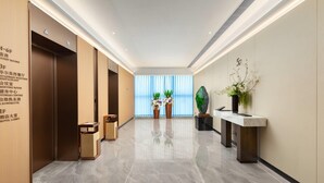 A hotel lobby with a marble floor, a reception desk, a flower arrangement, and a wall with room labels. - Ramada by Wyndham Zhaoqing Dawang (Zhaoqing)