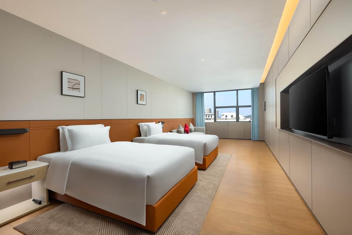 Habitació d'hotel amb dos llits, una televisió i un finestral gran.