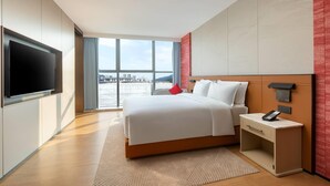 A modern hotel room with a large bed, a bedside telephone, and a TV mounted on the wall. - Ramada by Wyndham Zhaoqing Dawang (Zhaoqing)