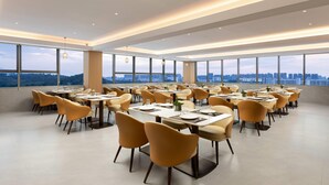 A spacious dining area with multiple tables and chairs, large windows offering a city view. - Ramada by Wyndham Zhaoqing Dawang (Zhaoqing)
