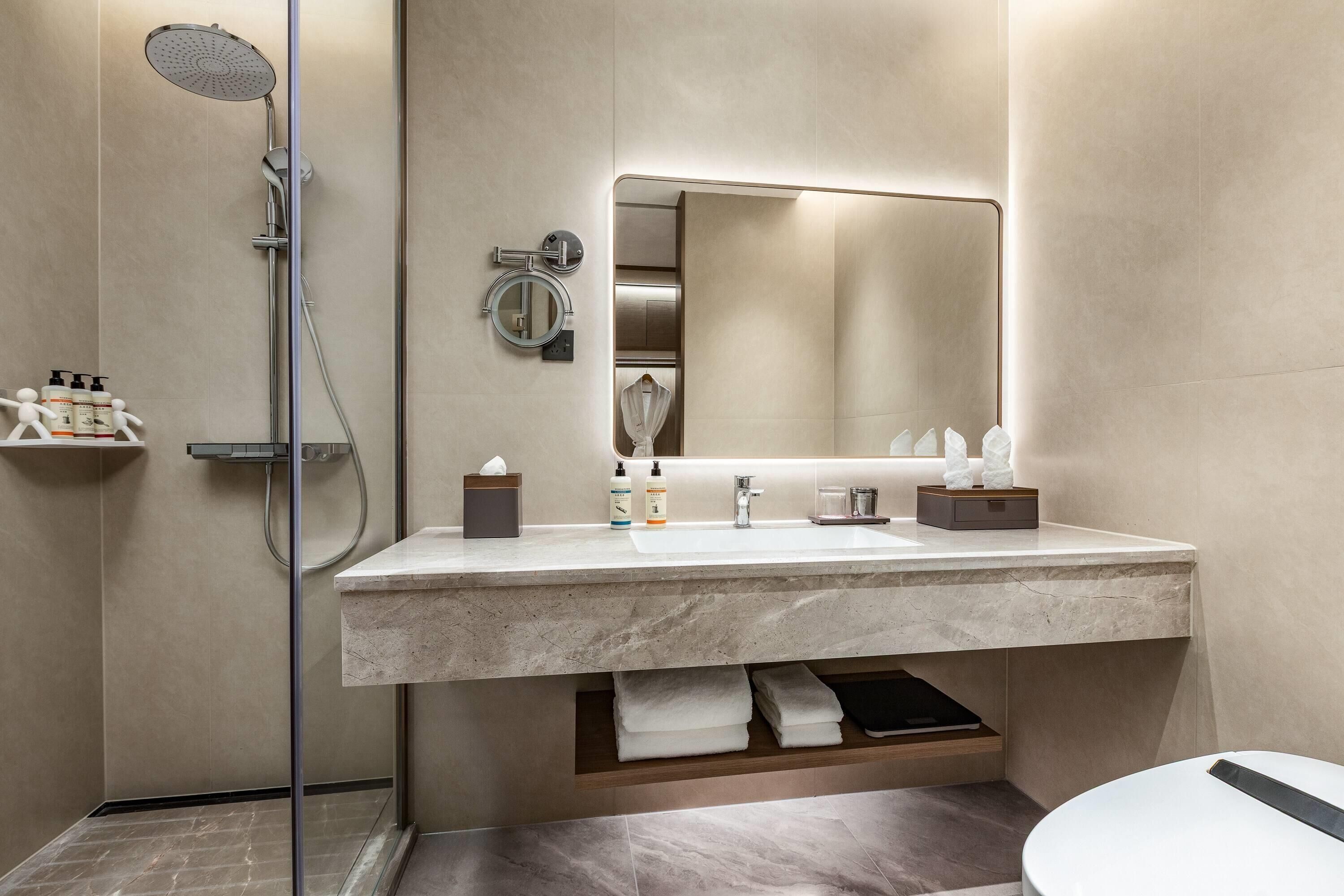 A modern bathroom with a shower, a sink with a mirror, and a towel rack.