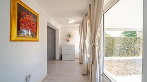 A hallway with a painting, a dresser, and a view of the outside. - Apartman Doris by Villas Guide (Vela Luka)