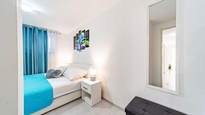 A bedroom with a bed, a nightstand, a mirror, and a view of the hallway. - Apartman Doris by Villas Guide (Vela Luka)