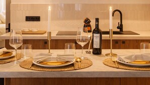 A modern kitchen with wooden cabinets, a white countertop, and a dining area set for a meal. - 1528 Nazareth (Paris)