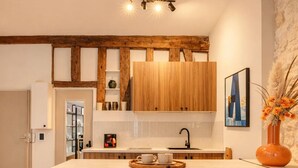 A modern kitchen with a central island, wooden cabinets, and a minimalist design. - 1528 Nazareth (Paris)