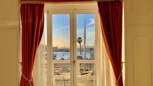 Une pièce dotée d’une porte vitrée donnant sur un balcon avec vue sur une marina et des bateaux.