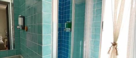 Une salle de bain avec des carreaux de couleur turquoise, une douche, un lavabo et un miroir.