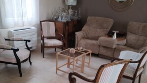 Un salon comprenant un canapé, des fauteuils, une table basse et un miroir décoratif.
