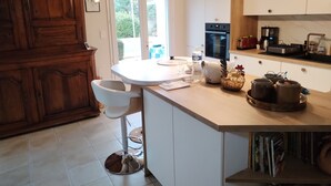 Une cuisine moderne dotée d’un îlot central, de meubles en bois, d’un four encastré et d’une machine à café.