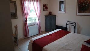 Une chambre à coucher avec un lit, une fenêtre avec des rideaux, une armoire et un radiateur.