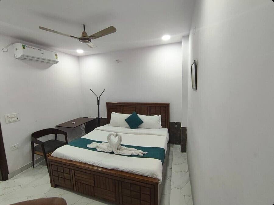 Un dormitorio con cama, escritorio, silla, ventilador de techo y aire acondicionado.