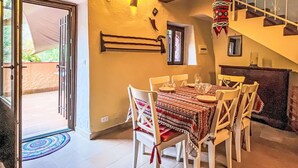 A dining area with a table set for four, a staircase, and a door leading outside. - Stunning  villa for 4 people with TV and terrace (Finale Ligure)