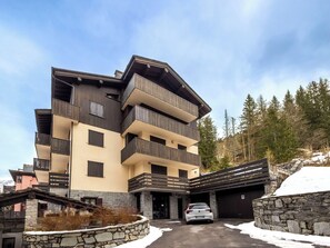 Ein mehrgeschossiges Gebäude mit Balkonen, einer Stein-Fassade und einem Auto davor.