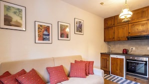 Ein gemütliches Wohnzimmer mit einer Couch, roten Kissen und gerahmten Kunstwerken an der Wand.