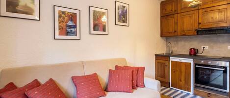 A cozy living room with a sofa, red pillows, and framed artwork on the wall.
