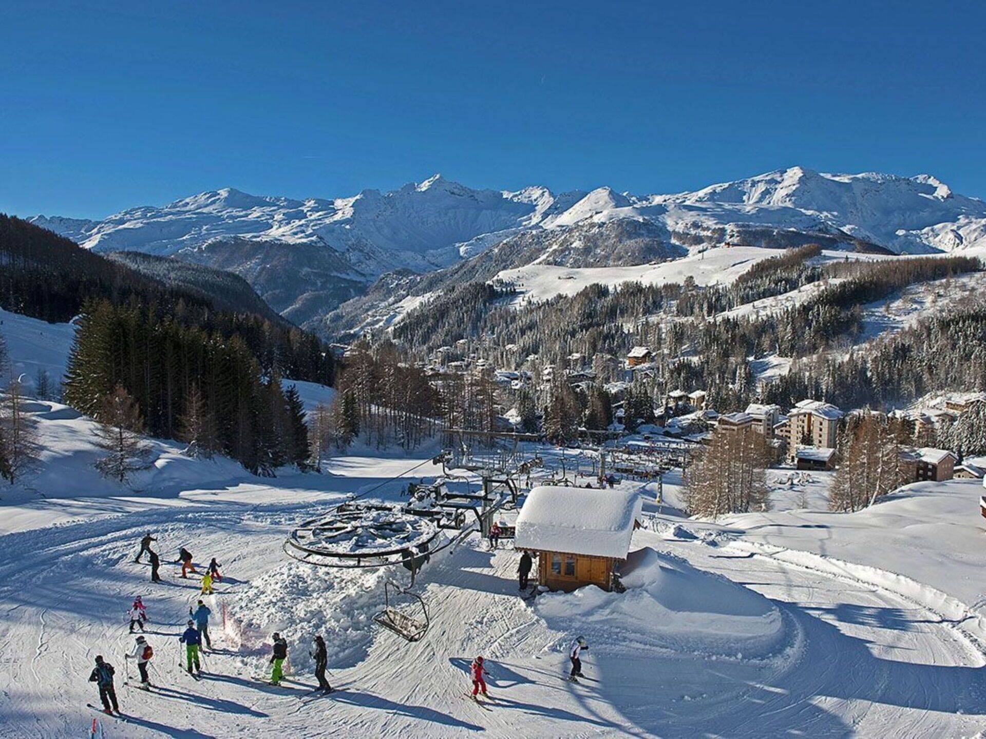A ski resort with a chairlift, snow-covered slopes, and a mountain backdrop.