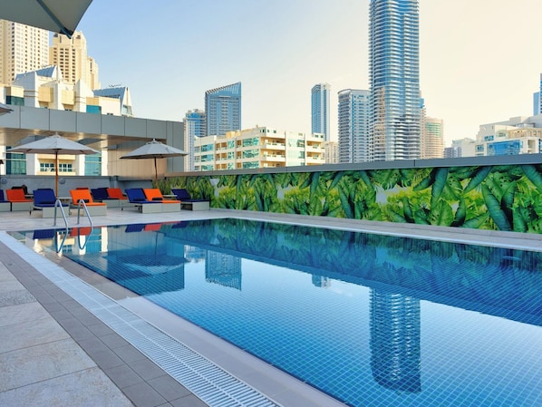 A swimming pool with lounge chairs and umbrellas, surrounded by high-rise buildings. - The First Collection Marina (Dubai)