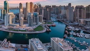 A cityscape with high-rise buildings, a marina, and a river. - The First Collection Marina (Dubai)