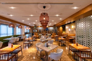 A modern restaurant interior with multiple dining tables, chairs, and a bar area. - The First Collection Marina (Dubai)