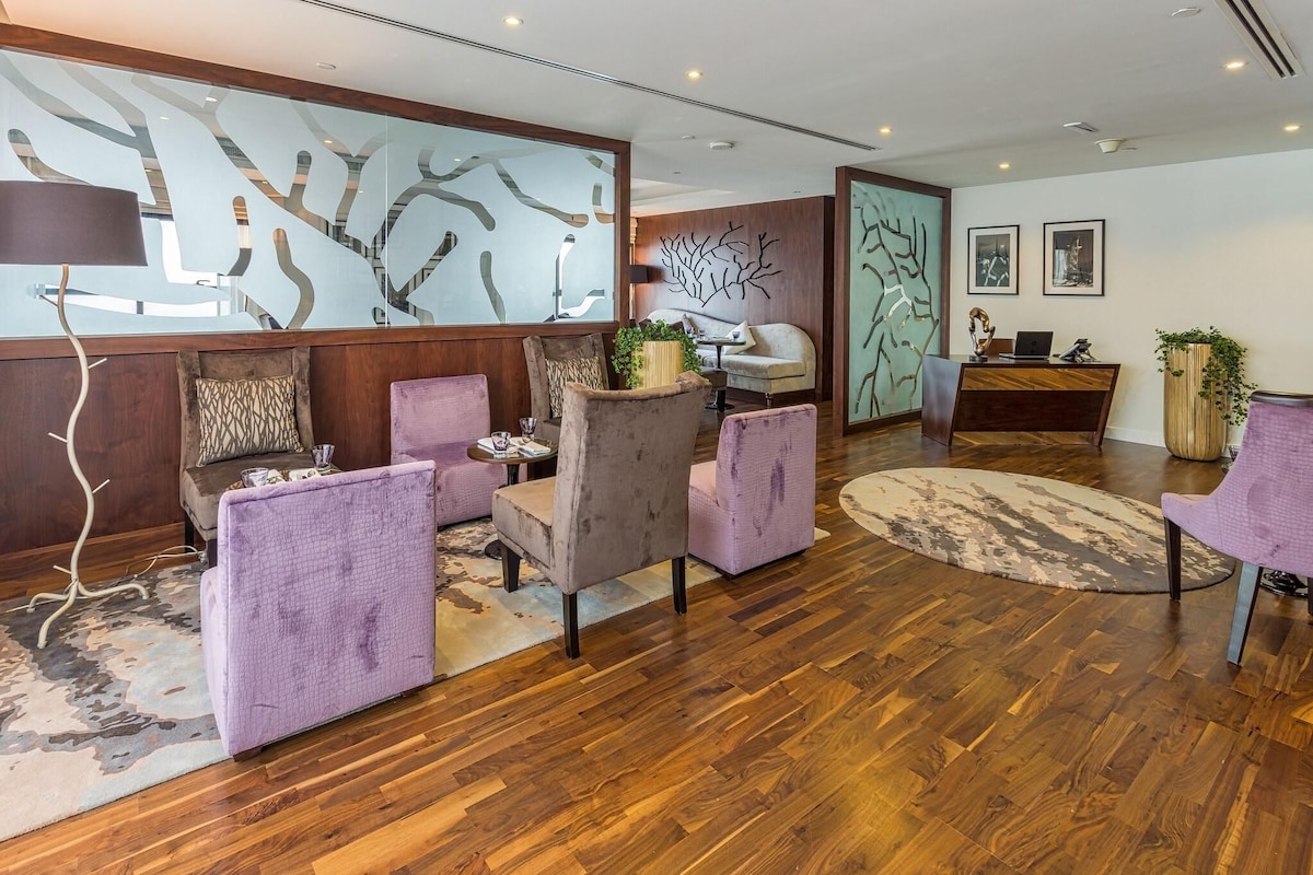 A modern lobby with wooden flooring, purple seating, and abstract wall art.